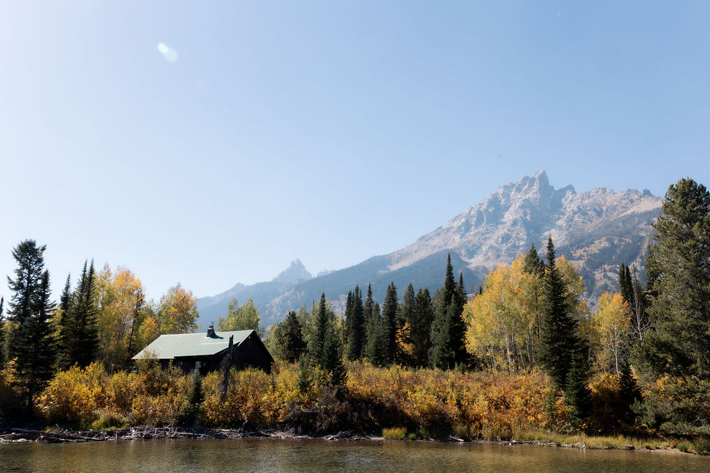 Film image of the picturesque Grand Teton Mountains in Jackson Hole Wyoming. There is a cabin and trees in the image