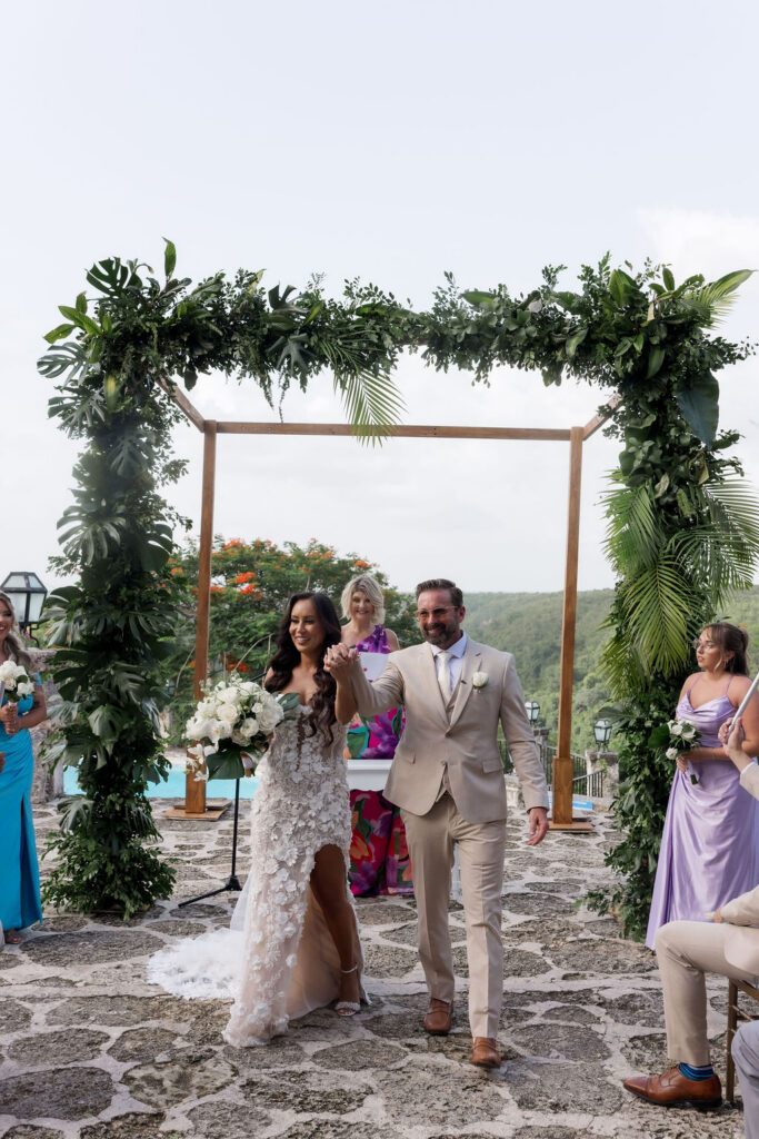 Intimate wedding ceremony with tropical florals and guests celebrating in a beautiful outdoor setting.