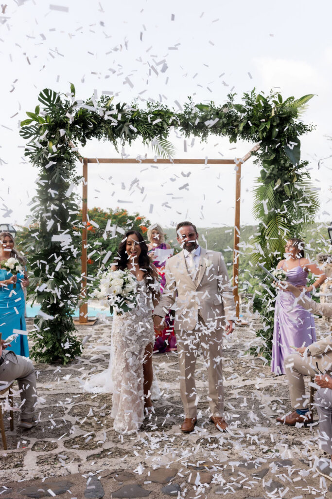 Intimate wedding ceremony with tropical florals and guests celebrating in a beautiful outdoor setting.